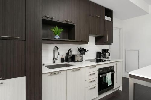 a kitchen with white counters and brown cabinets at 2BR 2BA Suite with Sofa Bed by Financial District in Toronto