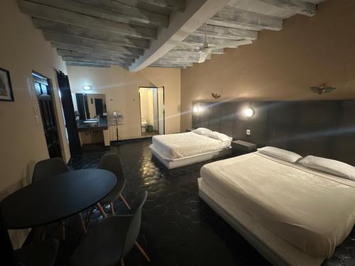 a hotel room with two beds and a table and chairs at La Casa del Mercado in San Miguel de Allende