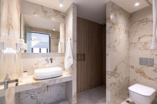 a bathroom with a sink and a toilet and a mirror at Pelago White in Skala Potamias