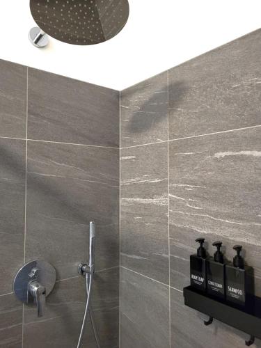 a bathroom with a shower with grey tiles at Rauchhof in Auer