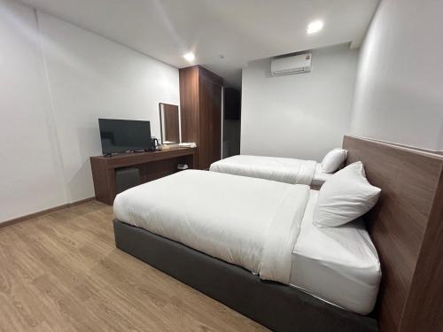 a hotel room with two beds and a television at J&P Hotel Sriracha in Ban Hua Na