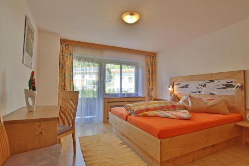 ein Schlafzimmer mit einem Bett mit orangefarbener Bettwäsche und einem Fenster in der Unterkunft Pension Plangger in Pfunds