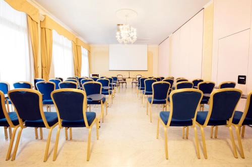 a room with chairs and a table and a screen at Grand Hotel President in Olbia