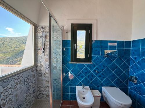 a blue tiled bathroom with a toilet and a shower at Baglio La Luna - B&B in San Vito lo Capo