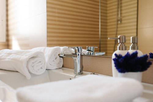 W łazience znajduje się umywalka, ręczniki i lustro. w obiekcie Hommyhome Pozo Santo Penthouse w Sewilli