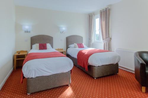 two beds in a room with red carpet at Wayford Bridge Inn Hotel in Stalham
