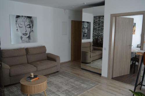 a living room with a couch and a table and a mirror at Wolkenfrei am Sonnenhang - Moderne Wohlfühl-Oase mit sonniger Süd-Terrasse in Lebach