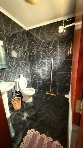 a black tiled bathroom with a toilet and a sink at Suítes Santa Luzia in Trindade