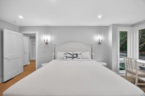 a white bedroom with a large bed and two chairs at 1395 Pelican Watch in Seabrook Island
