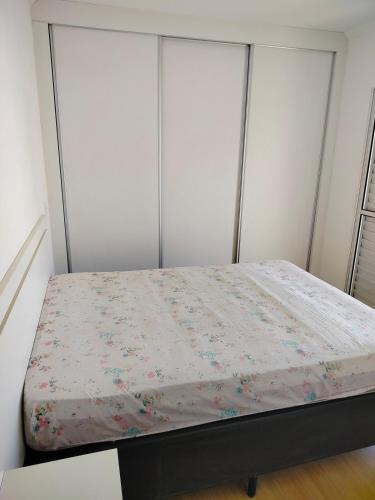 a bed in a bedroom with white walls at Ap 2quartos atras do shopping in Votorantim