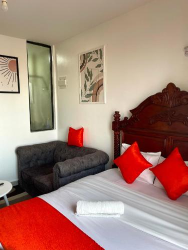 a bedroom with a bed with red pillows and a couch at T-Homes in Nairobi