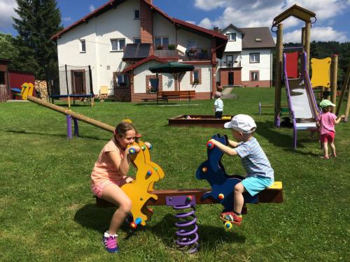 a woman and a child playing on a playground at Willa Hamernik AGROTURYSTYKA in Tylicz