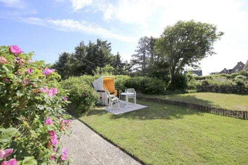 a garden with a table and chairs in the grass at Malvenhof, App OG in Wenningstedt