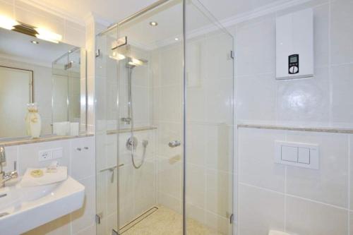 a white bathroom with a shower and a sink at Malvenhof, App OG in Wenningstedt