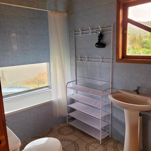 ein Badezimmer mit Waschbecken, Toilette und Fenster in der Unterkunft Chiloe Profundo in Chonchi