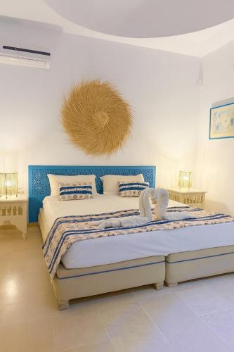 a bedroom with a large bed with a blue headboard at Dar Néliah Djerba in Djerba