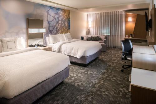 a hotel room with two beds and a desk at Courtyard by Marriott Jacksonville in Jacksonville