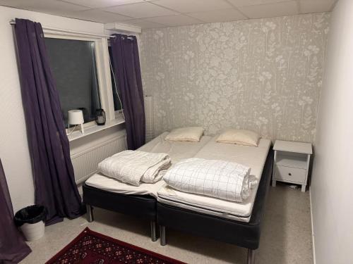 a small bedroom with a bed with purple curtains at Frövi vandrarhem in Frövi