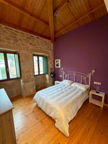 a bedroom with a large bed with a purple wall at A Casa de Feli in Muros