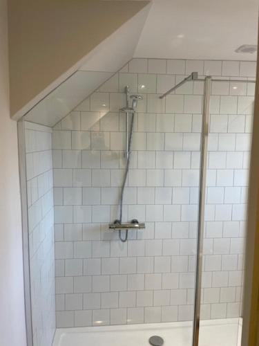 a shower in a bathroom with white tiles at Escape to Blacksmiths Cottage in Cuckfield