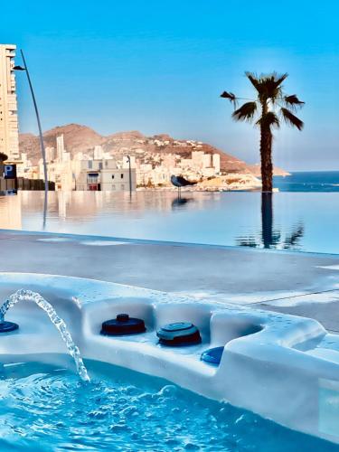 a swimming pool with a palm tree in the background at Sunset Cliffs Luxury Apartment Benidorm in Benidorm