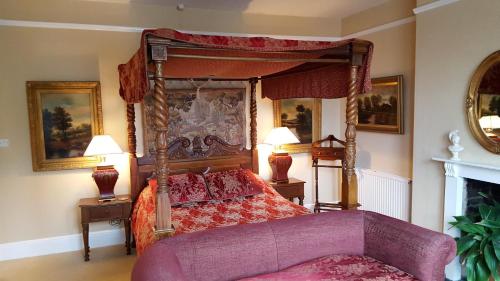 a bedroom with a canopy bed and a purple couch at Beggar's Knap in Dorchester
