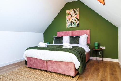 a bedroom with a large bed and a green wall at West London Spacious Modern House Garden Driveway in London