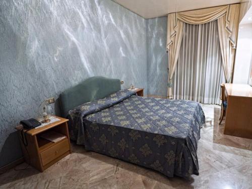 1 dormitorio con 1 cama y 1 mesa con mesita de noche en Sunny Palace Hotel Restaurant, en Prossedi