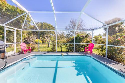 a swimming pool with two red chairs next to it at Relaxing 4 bedroom home with Pool in Punta Gorda