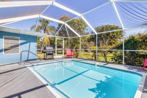 a swimming pool with a glass house with a table and chairs at Relaxing 4 bedroom home with Pool in Punta Gorda