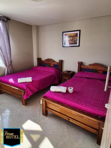 two beds in a room with pink sheets at Paraíso Hotel Ubaté in Ubaté