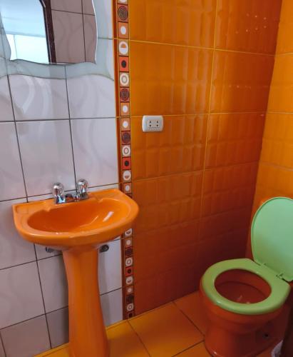 an orange sink and a toilet in a bathroom at Titicaca Backpacker in Puno
