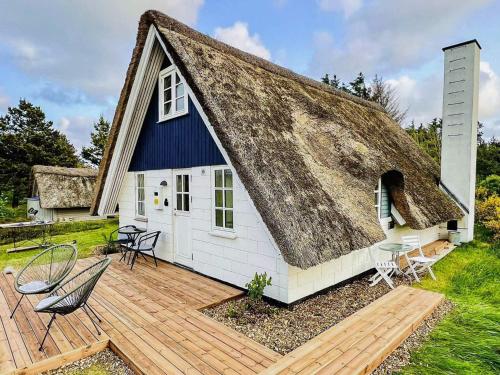 a house with a thatched roof with a wooden deck at 4 person holiday home in Ringkøbing-By Traum in Ringkøbing