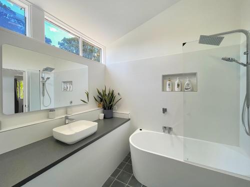 a white bathroom with a sink and a bath tub at Marlu Station in Broke