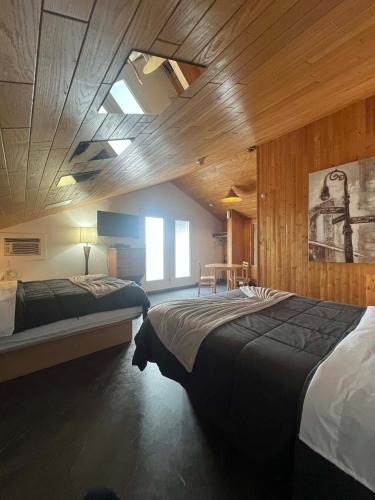 a bedroom with two beds and a wooden ceiling at Hôtel Auberge St-Félicien in Saint-Félicien
