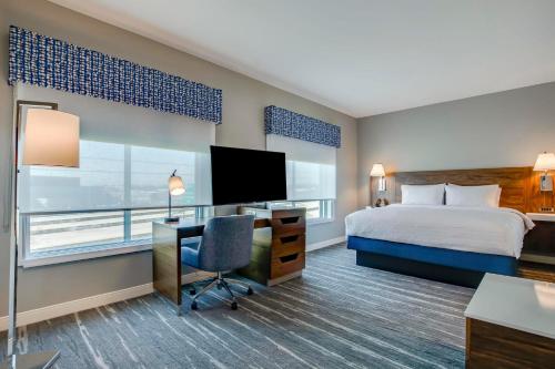 a hotel room with a bed and a desk and a television at Hampton Inn & Suites By Hilton Louisville East Oxmoor in Louisville