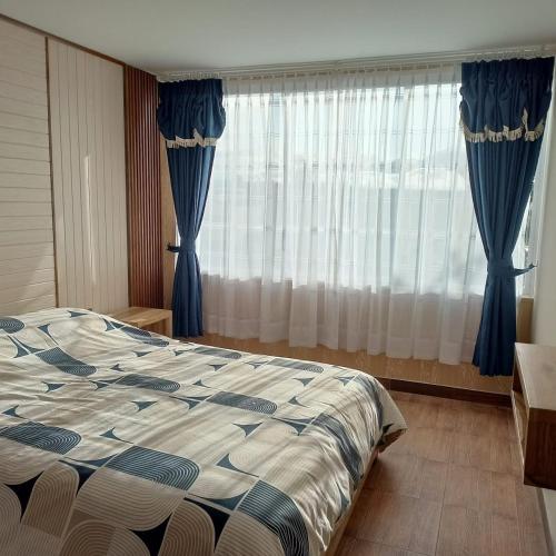 a bedroom with a bed and a window with curtains at Departamento azul de 2 hab en la Victoria, cerca de universidades con garaje in Ibarra