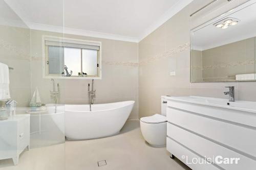 a white bathroom with a tub and a sink at Hills Bed & Breakfast in Pennant Hills