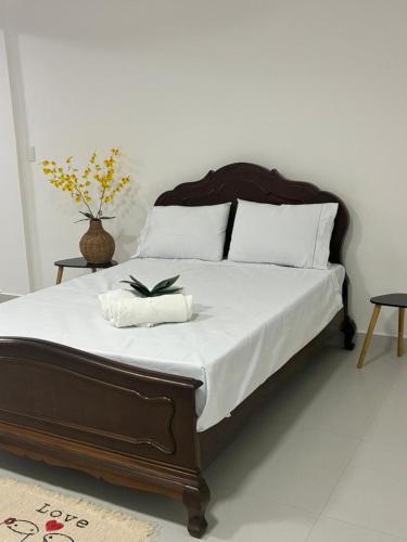a bed with white sheets and a book on it at Eco House1 in Santos