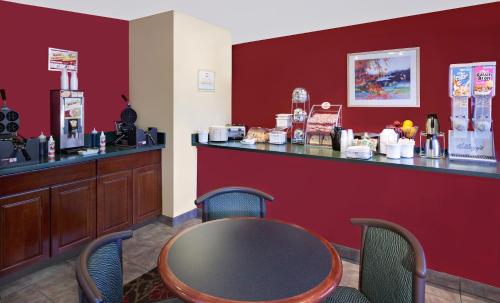 a restaurant with a table and chairs and a counter at Super 8 by Wyndham Mt. Pleasant in Mount Pleasant