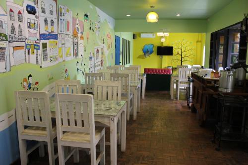 a dining room with white tables and white chairs at B-Cozy Hotel in Uttaradit