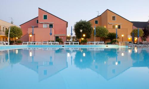 a large swimming pool with tables and buildings at Residence Borgomare in Albenga