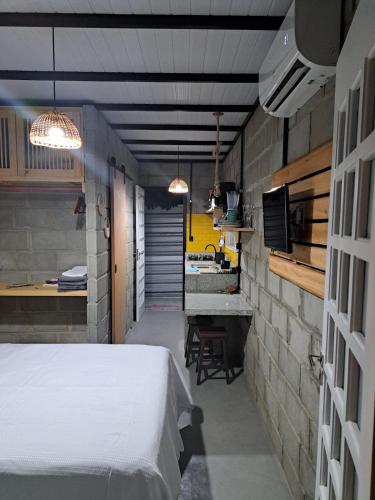 ein Schlafzimmer mit einem weißen Bett und eine Küche in der Unterkunft Rustica e Charmosa in Santa Cruz Cabrália