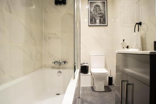 a white bathroom with a tub and a toilet at Luxury Serviced Apartment With Super King Bed Workspace WiFi & Netflix Washer Dryer Close Parking in Bradford