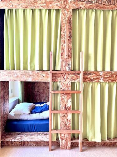 a bunk bed with a ladder in a room with green curtains at Agri Museum NADA - Vacation STAY 93817v in Minamiawaji
