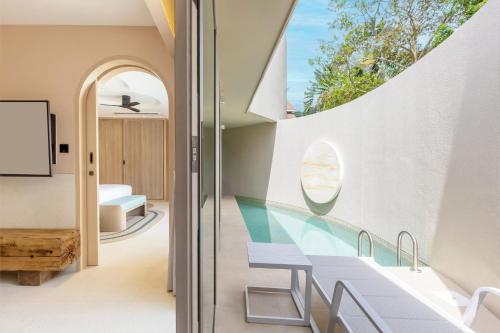 a room with a balcony with a table and a window at Centara Karon Villas Phuket in Karon Beach