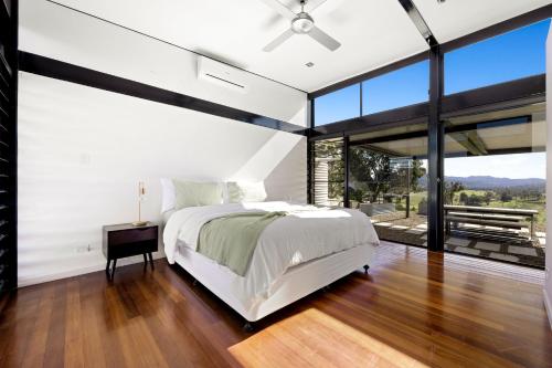 a bedroom with a large bed and large windows at Riverdance At Conondale in Conondale