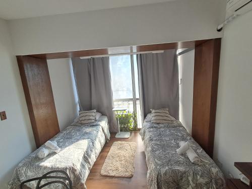 two beds in a room with a large window at C&MHouse in Buenos Aires