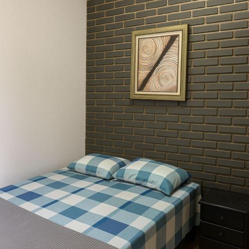 a bed in a room with a brick wall at Suítes Praia dos Sonhos in Itanhaém