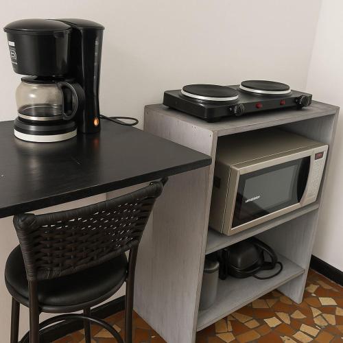a table with a coffee maker and a microwave at Suítes Praia dos Sonhos in Itanhaém
